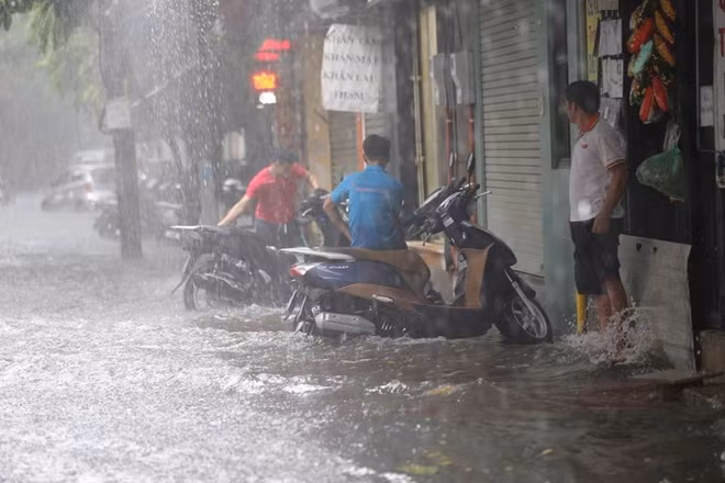 Nước dâng lên rất nhanh tràn từ lòng đường lên vỉa hè... và sau đó vào tới sát nhà dân.