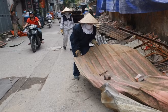 Trong khi đó một số người cũng đang thu dọn mảnh tôn từ nhà xưởng rơi ra đường sau vụ cháy.