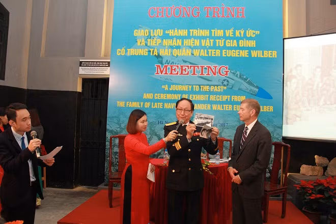 Đại tá Trần Trọng Duyệt - Nguyên Trại trưởng Trại giam tù binh phi công Mỹ tại Hỏa Lò, Hà Nội (giai đoạn 1968 - 1973) tặng bức ảnh của cựu phi công Walter cho con trai Thomas.