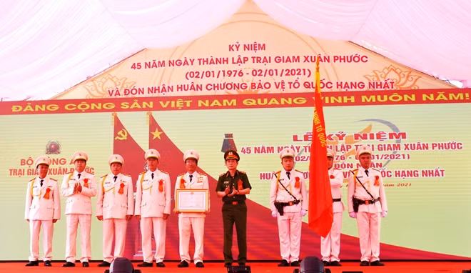Thừa ủy quyền của Chủ tịch Nước, Trung tướng Lê Minh Hùng trao và gắn Huân chương Bảo vệ Tổ quốc hạng Nhất lên cờ truyền thống của Trại giam Xuân Phước. Ảnh: Hữu Toàn