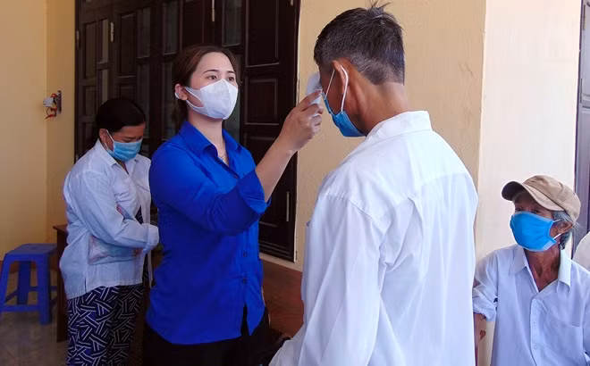Nữ đoàn viên thanh niên hỗ trợ đo thân nhiệt cho người dân đến điểm làm CCCD lưu động tại xã Đại Cường, huyện Đại Lộc.