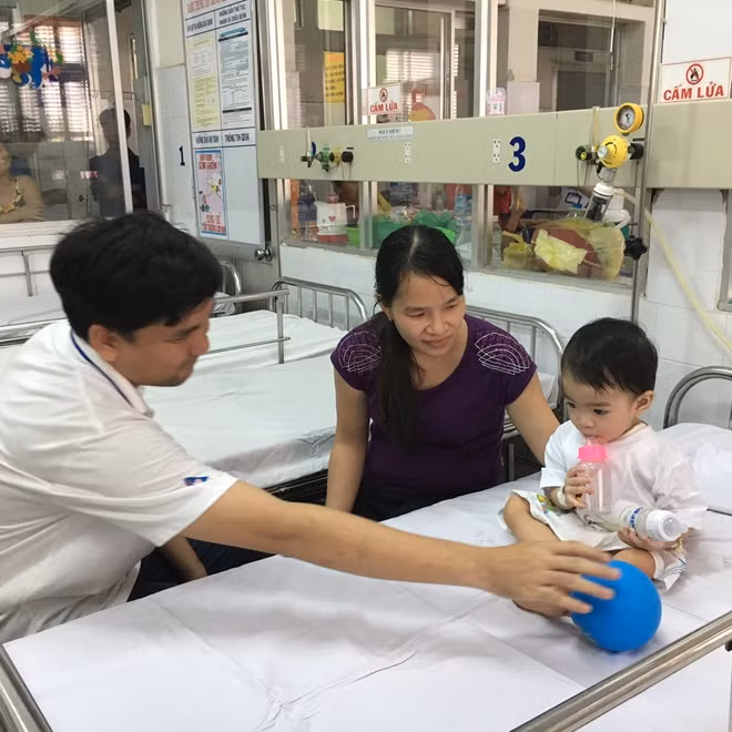 Bé D đã được cứu sống, ngồi chơi cùng cha mẹ tại bệnh viện Nhi đồng 1.