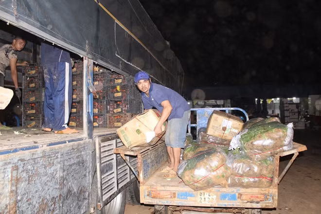 Hàng hoá đang được đưa từ trên xe xuống để vận chuyển vào sạp trong chợ