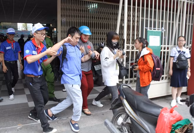 Thí sinh khuyết tật Trần Quốc Bảo được được các tình nguyện viên hỗ trợ tại điểm thi