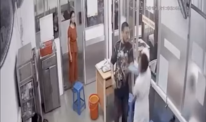 Nữ hộ sinh P.T.K.S (mặc áo nâu đứng ở cửa) được cho là đã chửi và xúi chồng đánh nữ điều dưỡng BV Nhi đồng 1 (Ảnh cắt từ clip). Nữ hộ sinh P.T.K.S (mặc áo nâu đứng ở cửa) được cho là đã chửi và xúi chồng đánh nữ điều dưỡng BV Nhi đồng 1 (Ảnh cắt từ clip).