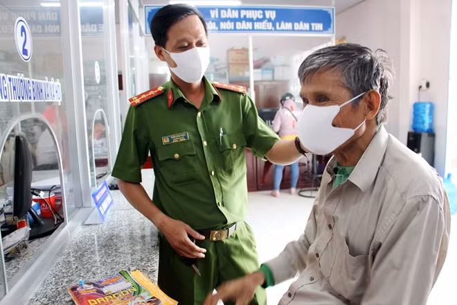 Cán bộ Công an xã Vĩnh Trinh hướng dẫn người dân đeo khẩu trang đúng quy định, góp phần phòng ngừa dịch COVID-19.