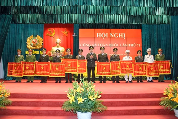 Thiếu tướng Nguyễn Đình Thuận, Cục trưởng Cục An ninh kinh tế tổng hợp (người đứng thứ 4 bên phải ảnh) nhận Cờ thi đua của Chính phủ do Bộ trưởng Trần Đại Quang trao tặng tại Hội nghị.