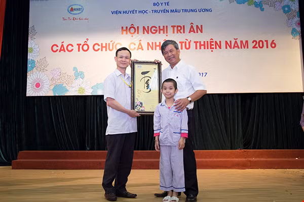 Cháu Phạm Hoàng Minh sau 5 tháng ghép tế bào gốc và bố được GS Nguyễn Anh Trí tặng bức tranh thư pháp.