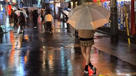 Một nữ sinh đứng trên đường phố Tokyo chờ khách hàng.