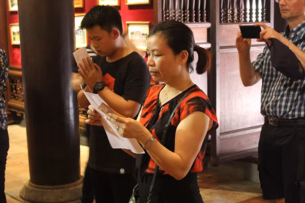 Một phụ huynh cầm giấy báo thi của con để khấn.