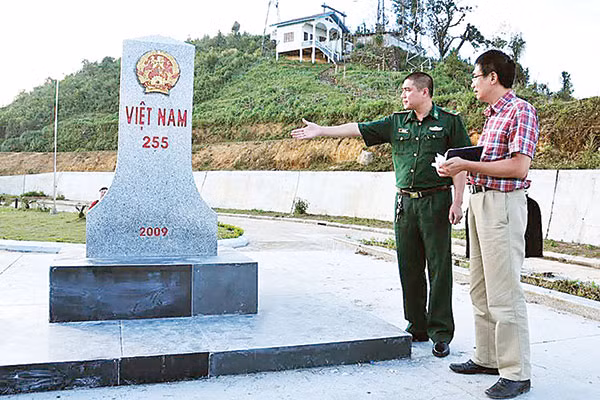 Thiếu tá Nguyễn Danh Tuệ - Đồn trưởng Đồn Biên phòng Lóng Sập và nhà văn Sương Nguyệt Minh bên cột mốc cửa khẩu.