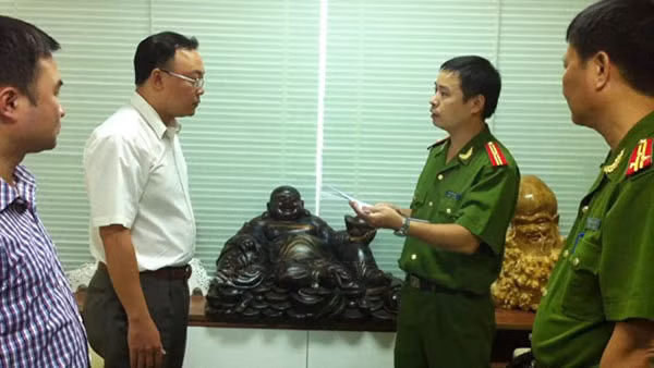Cơ quan điều tra đọc lệnh bắt giữ Saga (đeo kính).