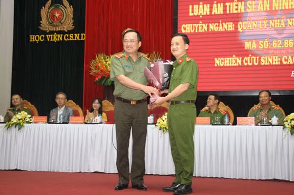 Nghiên cứu sinh Cao Hoàng Long tặng hoa chúc mừng Thượng tướng Nguyễn Văn Thành, Chủ tịch Hội đồng. Nghiên cứu sinh Cao Hoàng Long tặng hoa chúc mừng Thượng tướng Nguyễn Văn Thành, Chủ tịch Hội đồng.