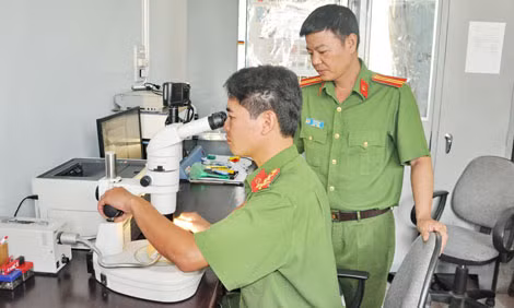 Thiếu tá Vũ Thế Nam cùng giám định viên Phòng KTHS Công an tỉnh Khánh Hòa giám định tài liệu trên thiết bị công nghệ hiện đại.