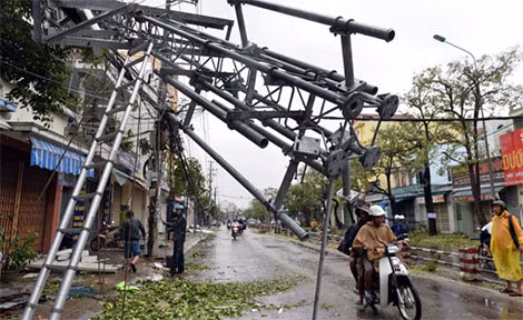Bên cạnh nhà bà Hồng, một chiếc cột thu phát sóng viễn thông đổ ập, đè lên mái nhà và đường dây điện.