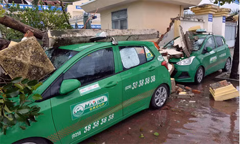 Hai chiếc taxi đỗ cạnh trường Tiểu học Phước Thịnh, Hòn Rớ, bị tường đổ đè bẹp.