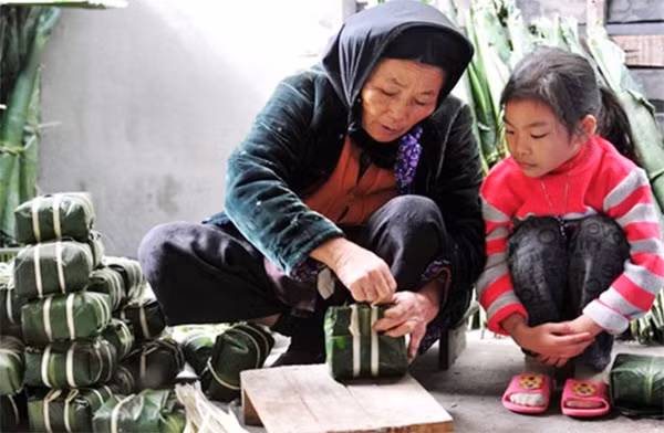 Bà dạy cháu gói bánh chưng ngày Tết cổ truyền.