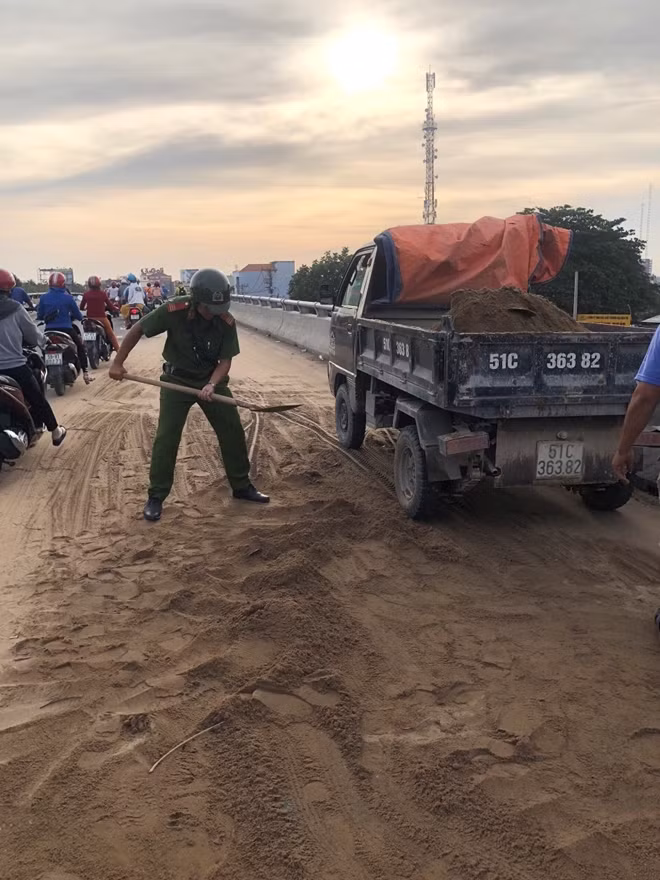 Chiến sĩ Cảnh sát trật tự xúc cát rơi vãi trên mặt đường.