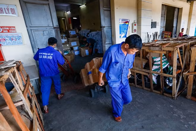 Các công nhân đường sắt vận chuyển hàng hoá từ nhà kho ra toa xe hàng.