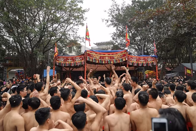 Bên ngoài, hàng trăm trai tráng cởi trần đợi đến phần kiệu 4 ông quan đám diễn trò, múa tại sân đình. Họ được các thanh niên cởi trần, mặc quần đùi đỏ tung hô và giữ chắc ở trên cao.