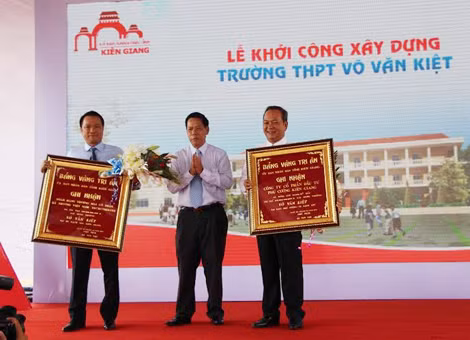 Ông Nguyễn Việt Cường, đại diện công ty Phú Cường (phải) được lãnh đạo UBND tỉnh Kiên Giang trao bảng vàng tri ân đã đóng góp 20.000m2 đất trị giá 100 tỷ đồng xây dựng trường THPT Võ Văn Kiệt