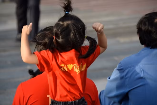Một bé gái theo ba ra "xí" chỗ ngồi để xem bóng đá