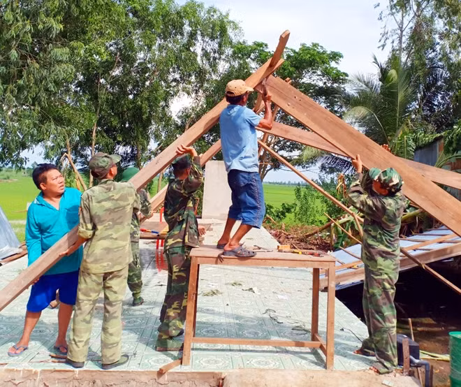 Lực lượng chức năng hỗ trợ người dân dựng lại nhà.