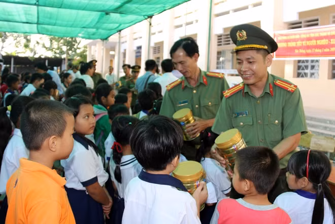 Đại diện Phòng Công tác Chính trị và Công tác Đảng Công an tỉnh Sóc Trăng trao sữa cho em học sinh.