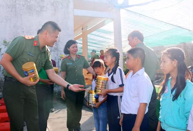Thiếu tá Nguyễn Văn Bình trao tặng sữa cho các em học sinh.
