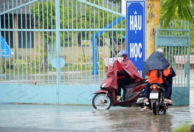Phụ huynh đưa con em đến điểm thi trong cơn mưa nặng hạt.