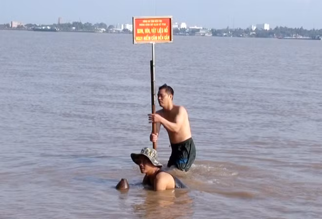 Lực lượng chức năng tiến hành thu gom quả bom nặng gần 100 kg tại bãi bồi.