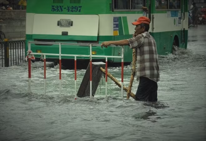 Người đàn ông đứng chịu trận ngay miệng cống để không cho các phương tiện qua khu vực nguy hiểm này