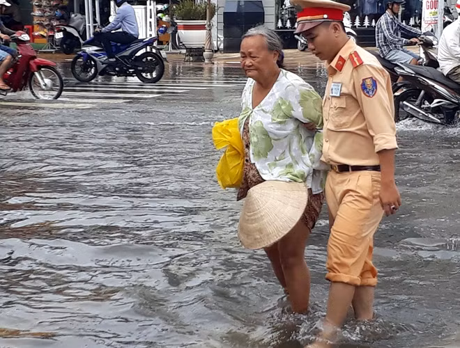 Lực lượng CSGT Công an Bạc Liêu, giúp người dân vượt qua những đoạn đường ngập sâu.
