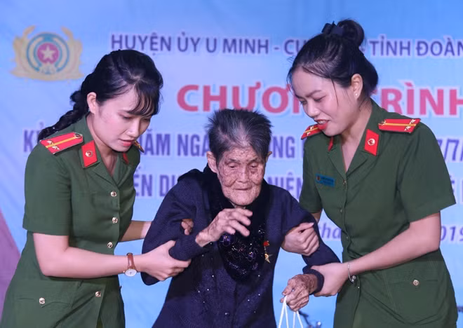Cán bộ Trại giam Cái Tàu đỡ Mẹ VNAH Trương Thị Thắm lên nhận quà.