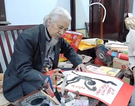 Nhà thư pháp Lê Thiên Lý đang viết thư pháp hình con khỉ.