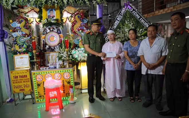 Thiếu tá Nguyễn Thái Bình trao số tiền hỗ trợ của báo CAND cho gia đình anh Quang.