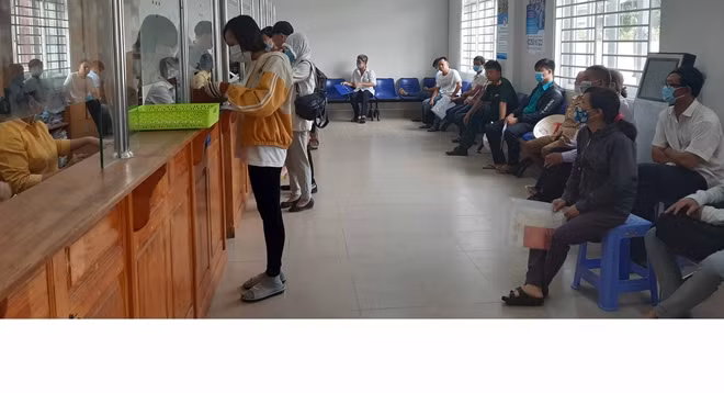 Người dân đeo khẩu trang và tự ngồi giãn cách khi đến làm thủ tục ở công sở.