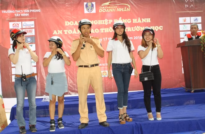 Cán bộ CSGT hướng dẫn học sinh đội mũ bảo hiểm đúng cách