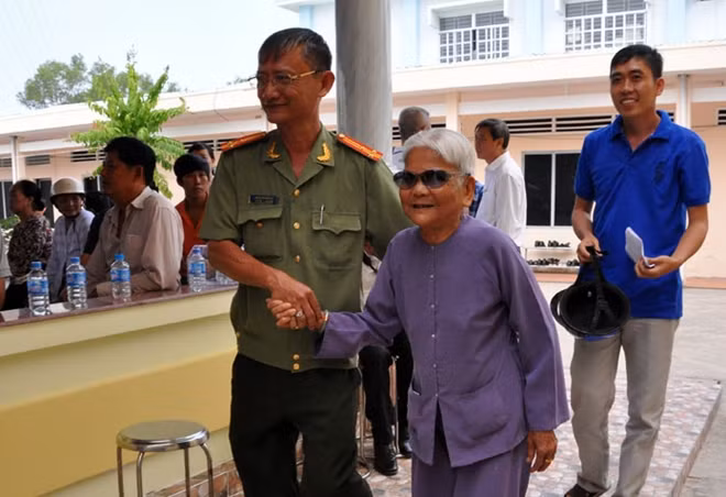 Cán bộ Công an huyện dắt tay Mẹ VNAH Nguyễn Thị Hạnh tới tận chỗ ngồi dự buổi lễ.
