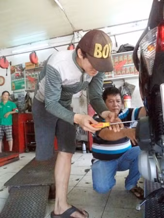 Ông Phúc đang tận tình hướng dẫn học trò tàn tật sửa xe.