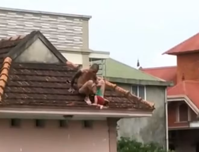 Đối tượng ôm con trai ngồi la hét trên mái nhà
