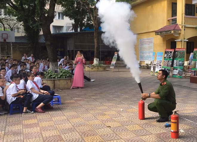 Cán bộ Công an quận Đống Đa hướng dẫn các em học sinh cách sử dụng bình chữa cháy