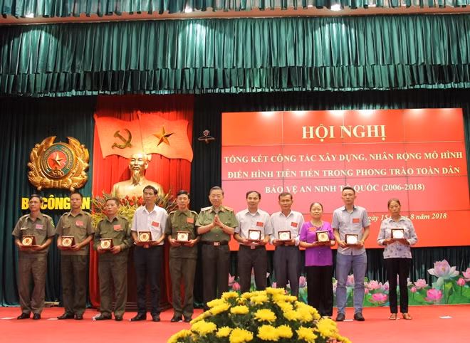 Bộ trưởng Tô Lâm trao quà và logo phong trào Toàn dân bảo vệ ANTQ tặng đại diện các gia đình liệt sỹ, thương binh là Công an xã, Bảo vệ dân phố