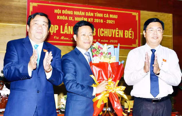 Ông Nguyễn Tiến Hải (bìa phải), Bí thư Tỉnh ủy Cà Mau, tặng hoa chúc mừng ông Lê Quân (giữa), tân Chủ tịch UBND tỉnh Cà Mau.