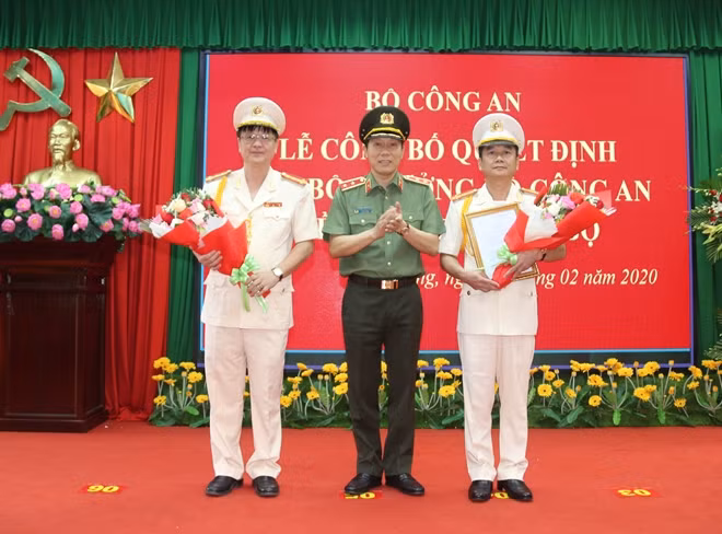 Thứ trưởng Lương Tam Quang, trao quyết định, tặng hoa Đại tá Nguyễn Minh Ngọc (bên phải) và tặng hoa Đại tá Lê Minh Quang (bên trái).