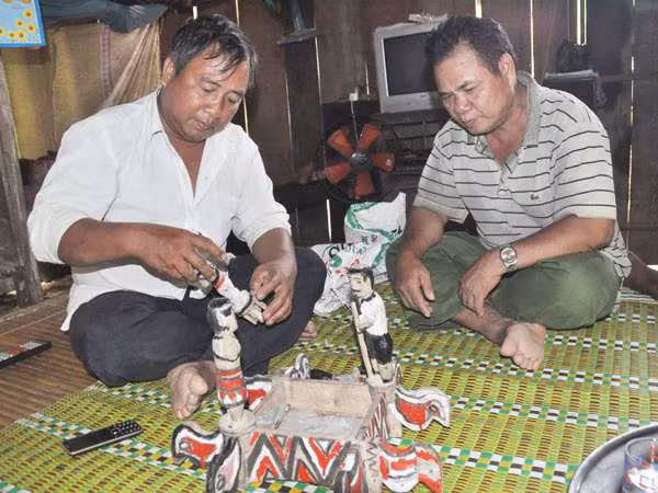 Ông Ta Rương Mão (trái) và nghệ nhân Ta Rương Via giới thiệu về tượng nhà mồ của đồng bào Cơ Tu.