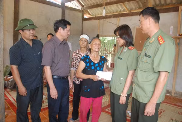 Đại úy Cao Thị Hồng - Phó trưởng Ban pháp luật - Bạn đọc Báo CAND, lãnh đạo UBND, Công an huyện Văn Yên thăm hỏi, hỗ trợ gia đình bà Hoàng Thị Say 30 triệu đồng - số tiền do Công ty Duy Lợi ủng hộ.