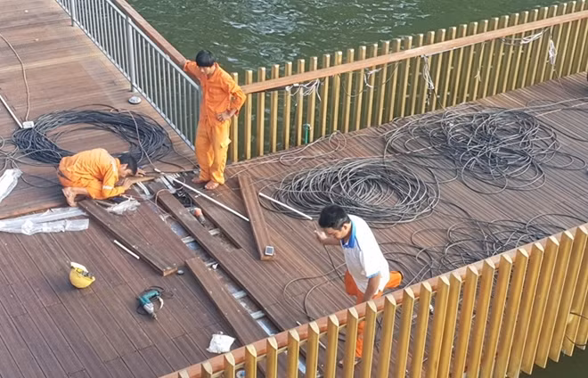 Công nhân điện lực đang lắp đặt hệ thống chiếu sáng trên cầu.