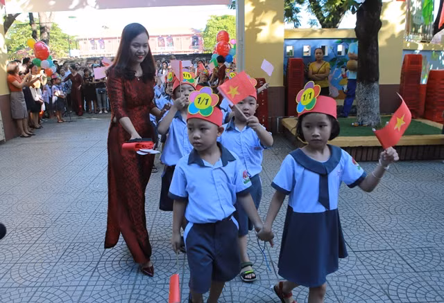 Các em học sinh trường Tiểu học Vĩnh Ninh được cô giáo dẫn vào trường tham dự lễ khai giảng.