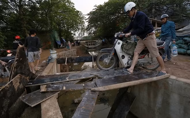 Để thoát khỏi đoạn ùn tắc kéo dài và đoạn đường lầy lội, nhiều người lại tìm cách vượt qua mương nước bằng những tấm ván gỗ ép.